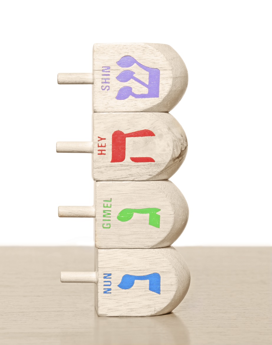 Stack of 4 Chanukah wooden dreidels laying on a wood surface