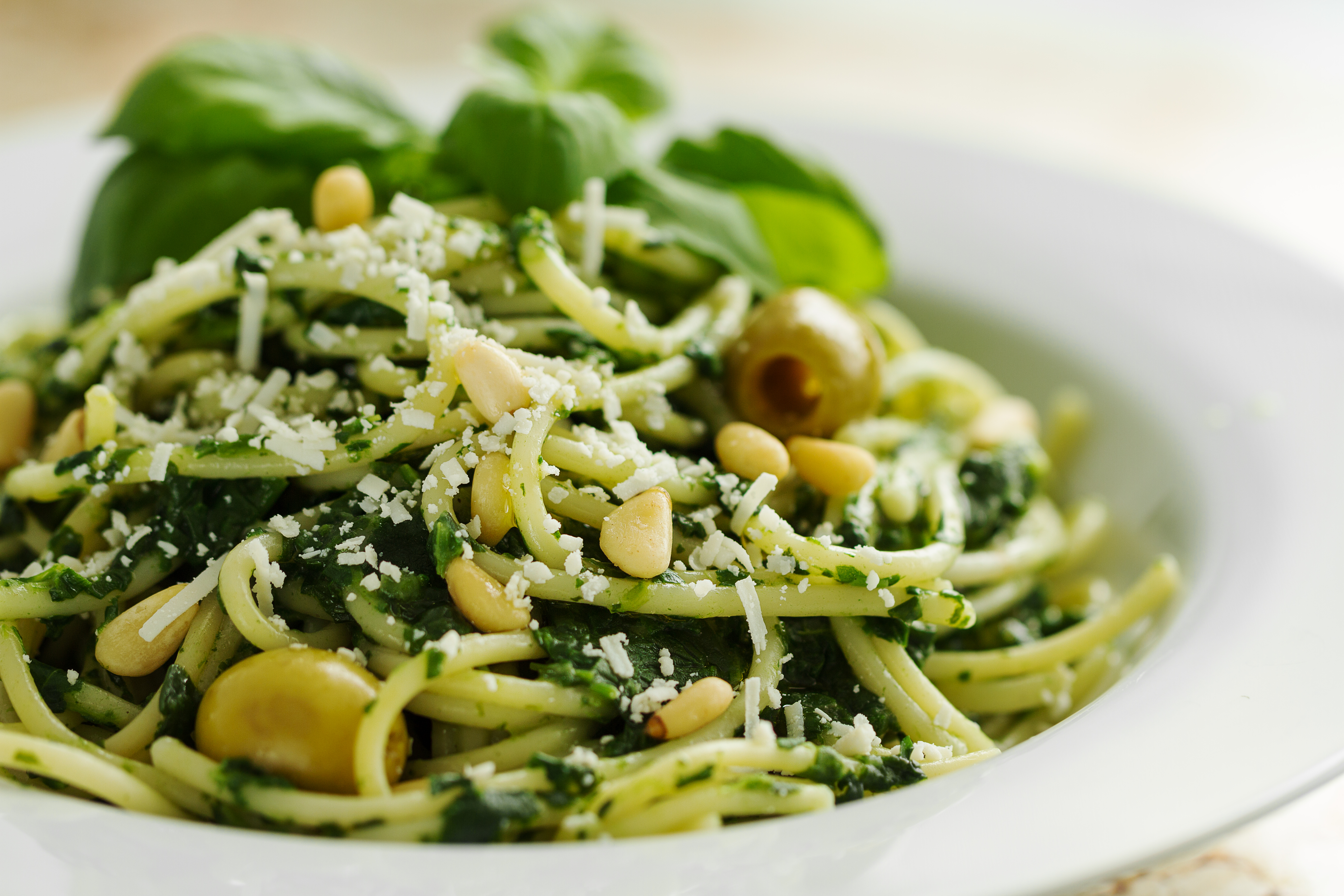 Tasty Beautiful Pasta Closeup with Spinach, Cheese, Olives, Basil and Nuts.