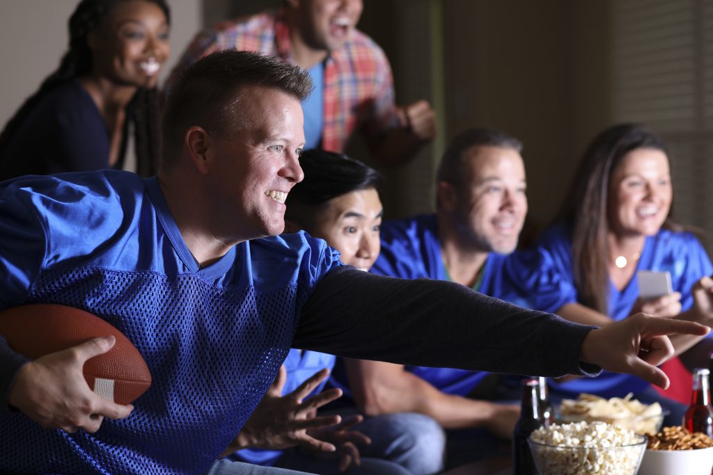 Football fans watching the game at home on television.