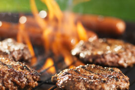 hamburgers and hotdogs cooking on flaming grill hamburgers and hotdogs cooking on flaming grill shot with selective focus