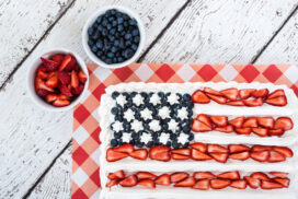 Patriotic American flag cake with blueberries and strawberries on vintage white background