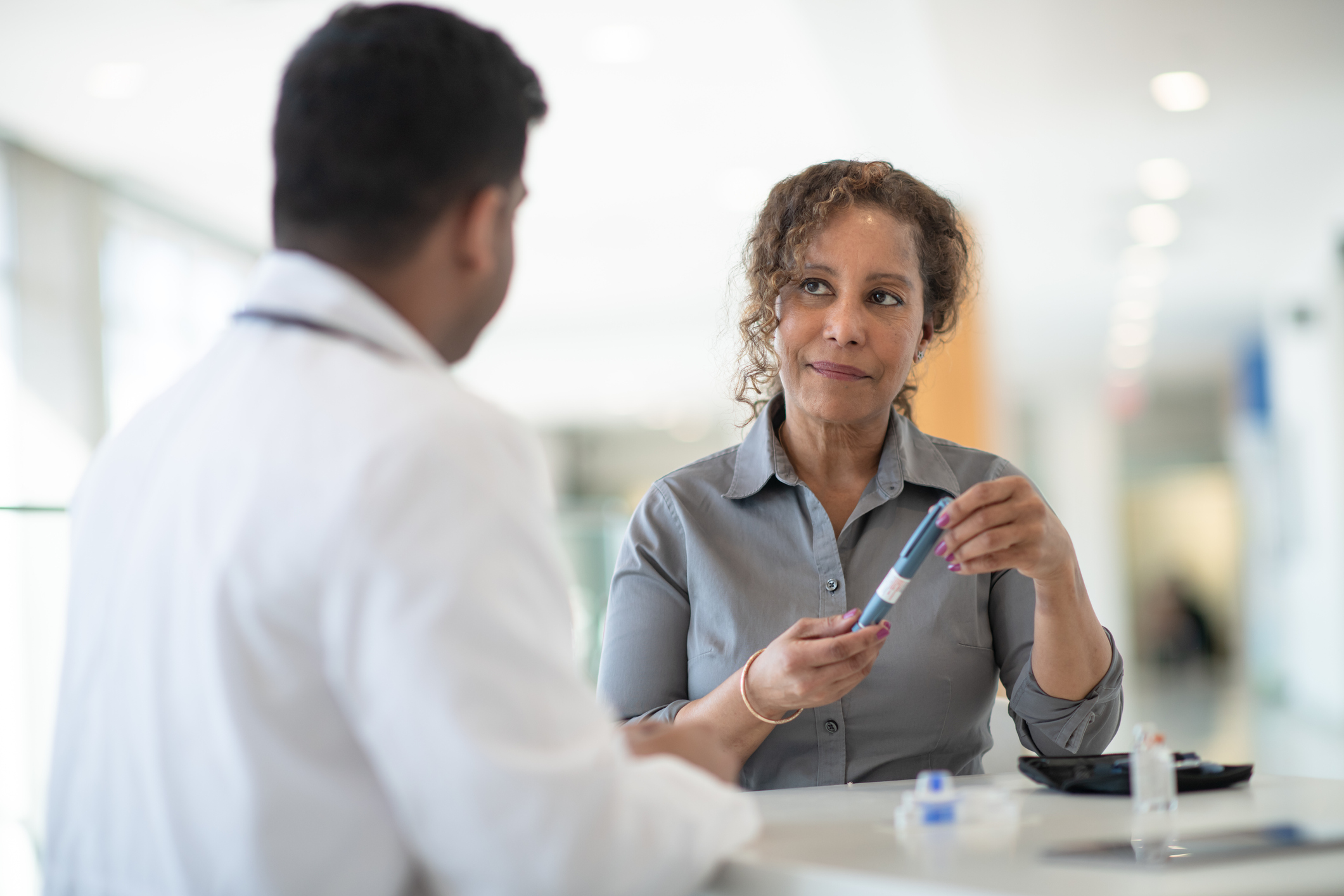 A woman discusses with her doctor about possibilities for diabetes treatment in a well lit medical facility.