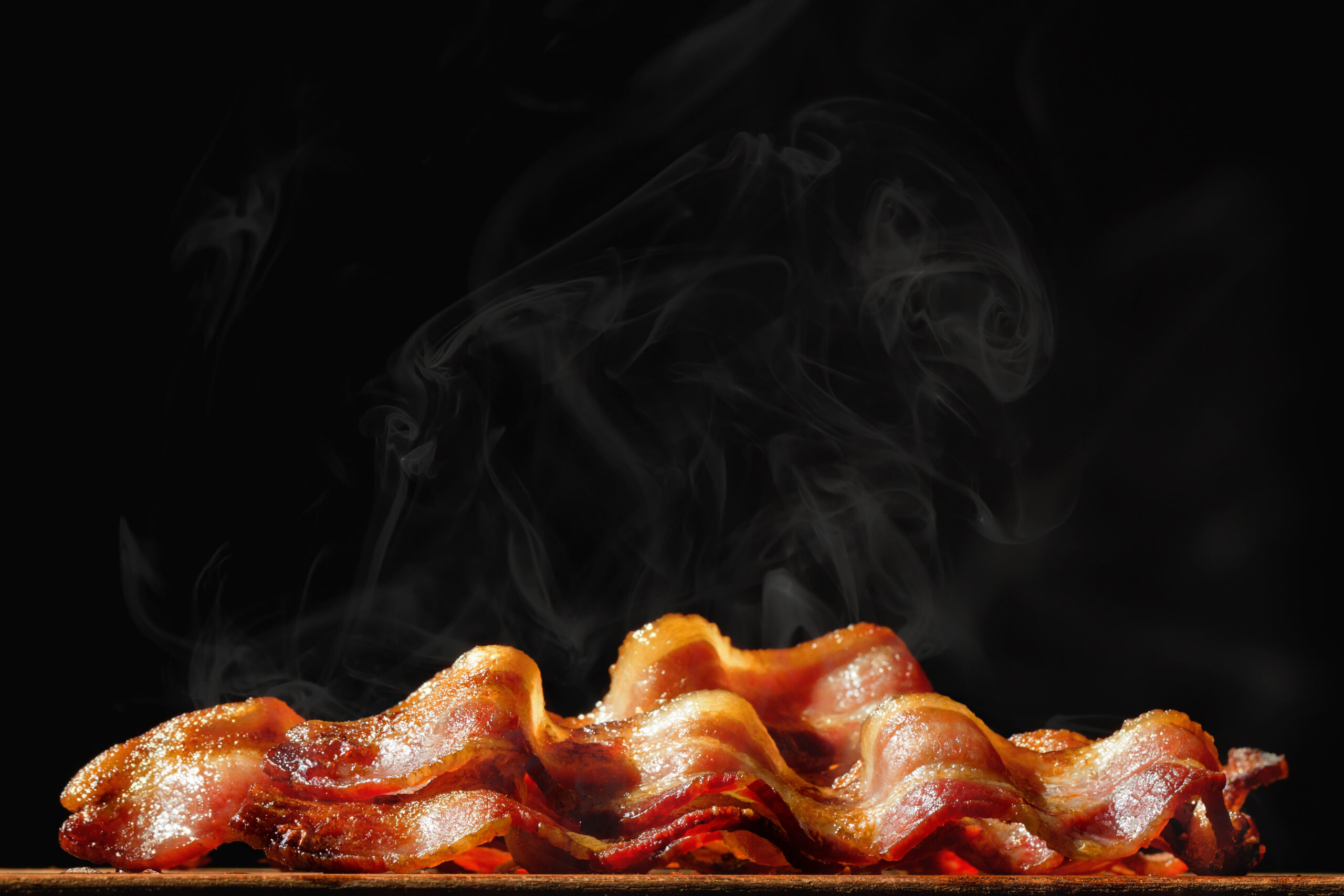 Pile of steaming hot freshly cooked bacon with room for text in black background
