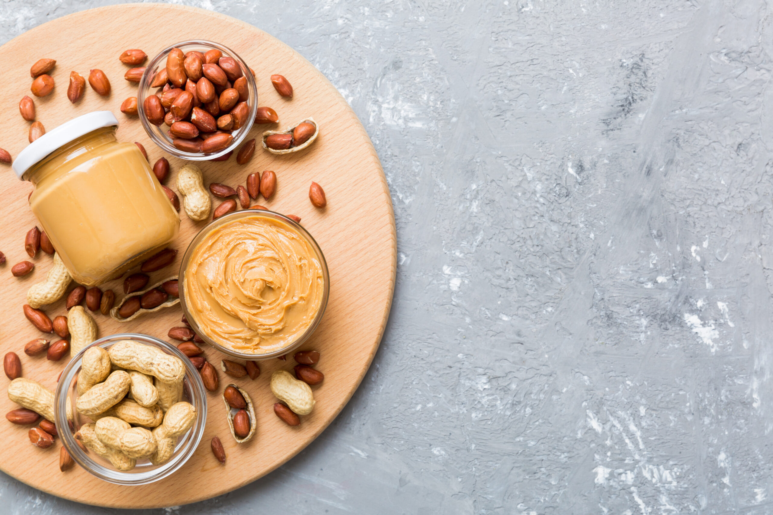 Bowl of peanut butter and peanuts on table background. top view with copy space. Creamy peanut pasta in small bowl.