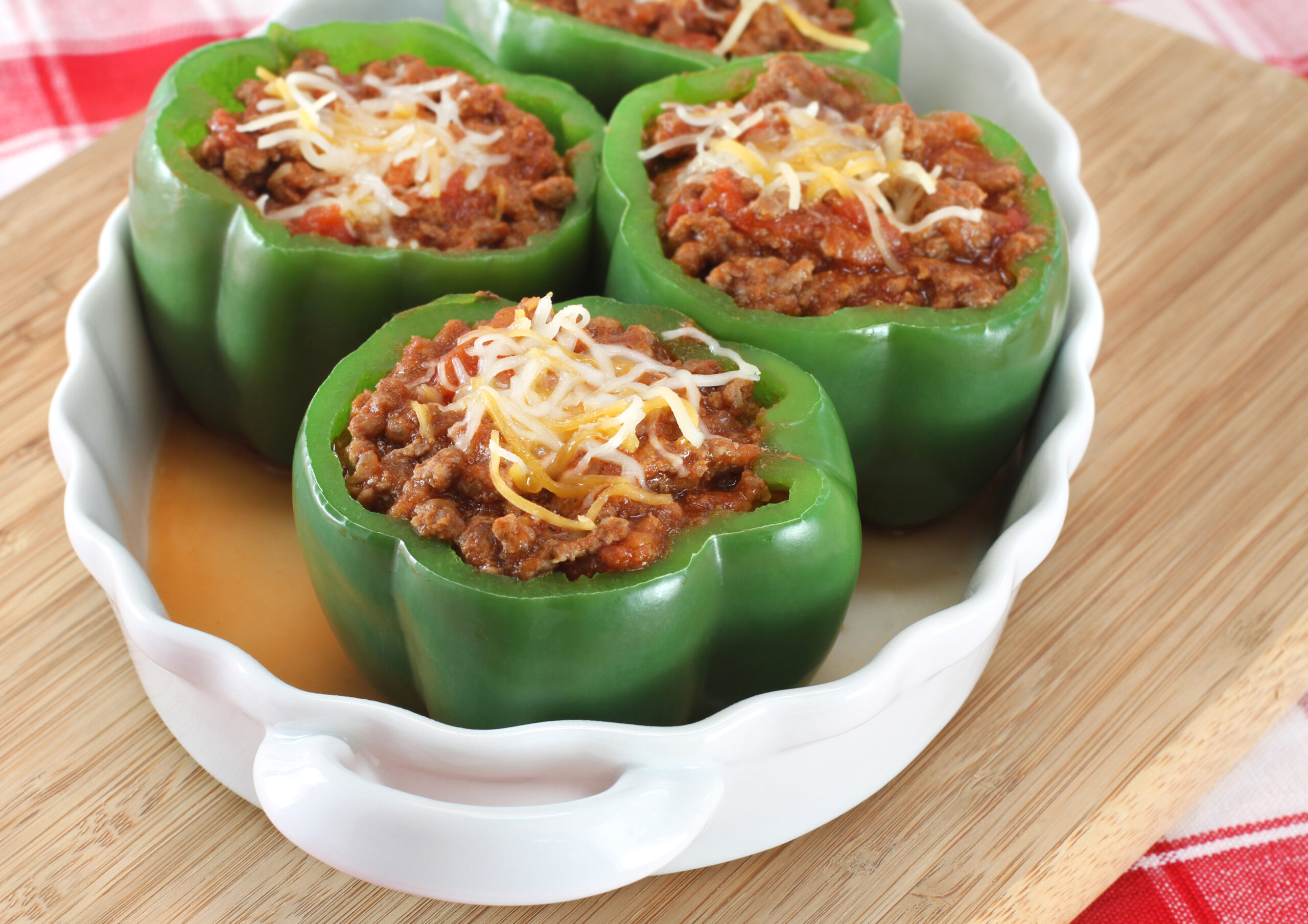 Oval baking dish of stuffed green peppers with selective focus on foremost pepper.