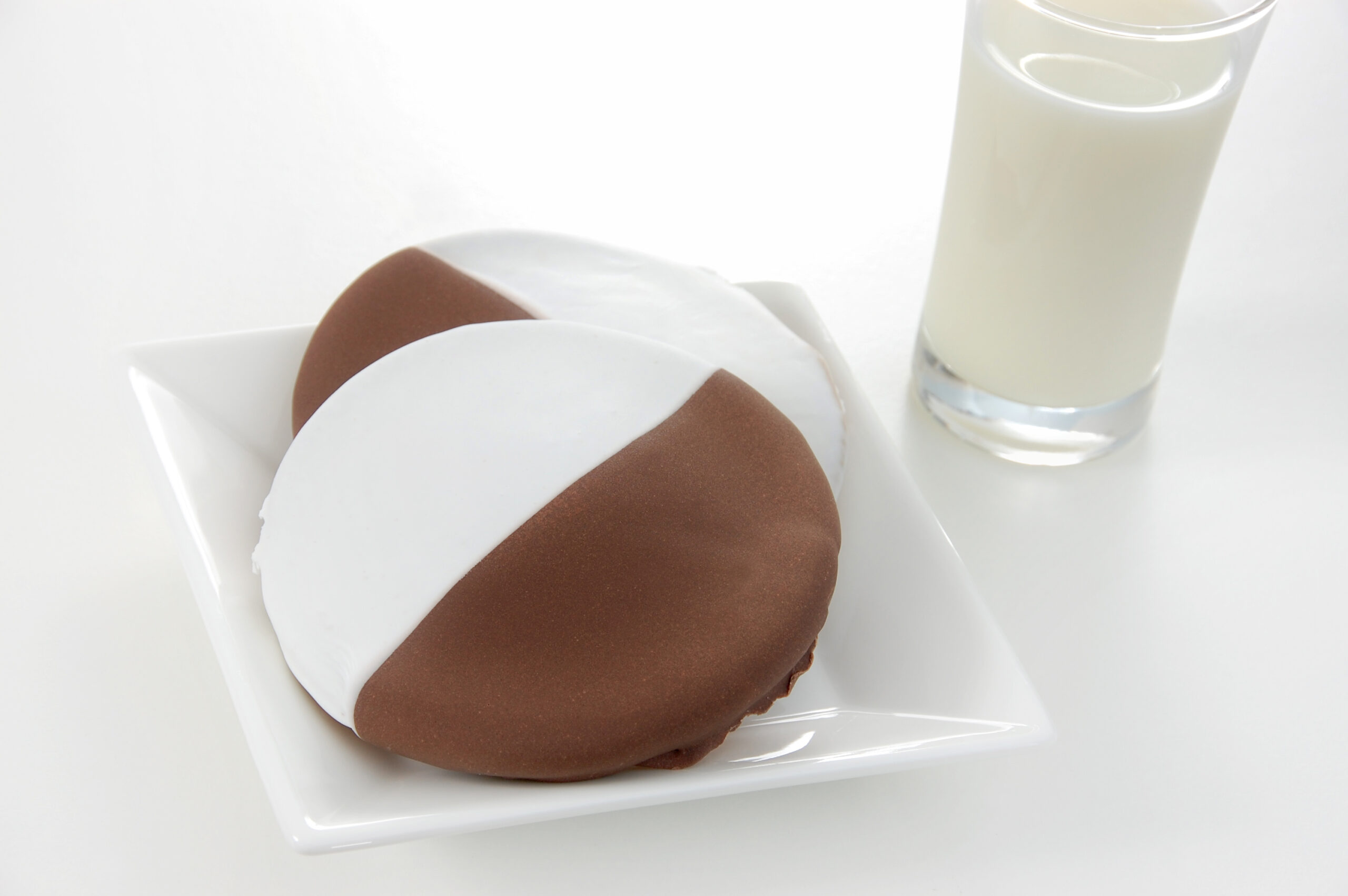 American traditional black and white or half moon cookies served with a glass of cold milk.