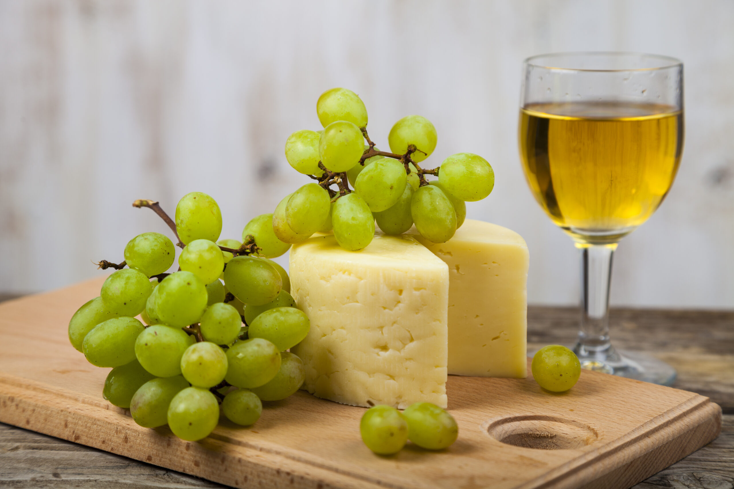 White wine, cheese and grapes on an old wooden table.