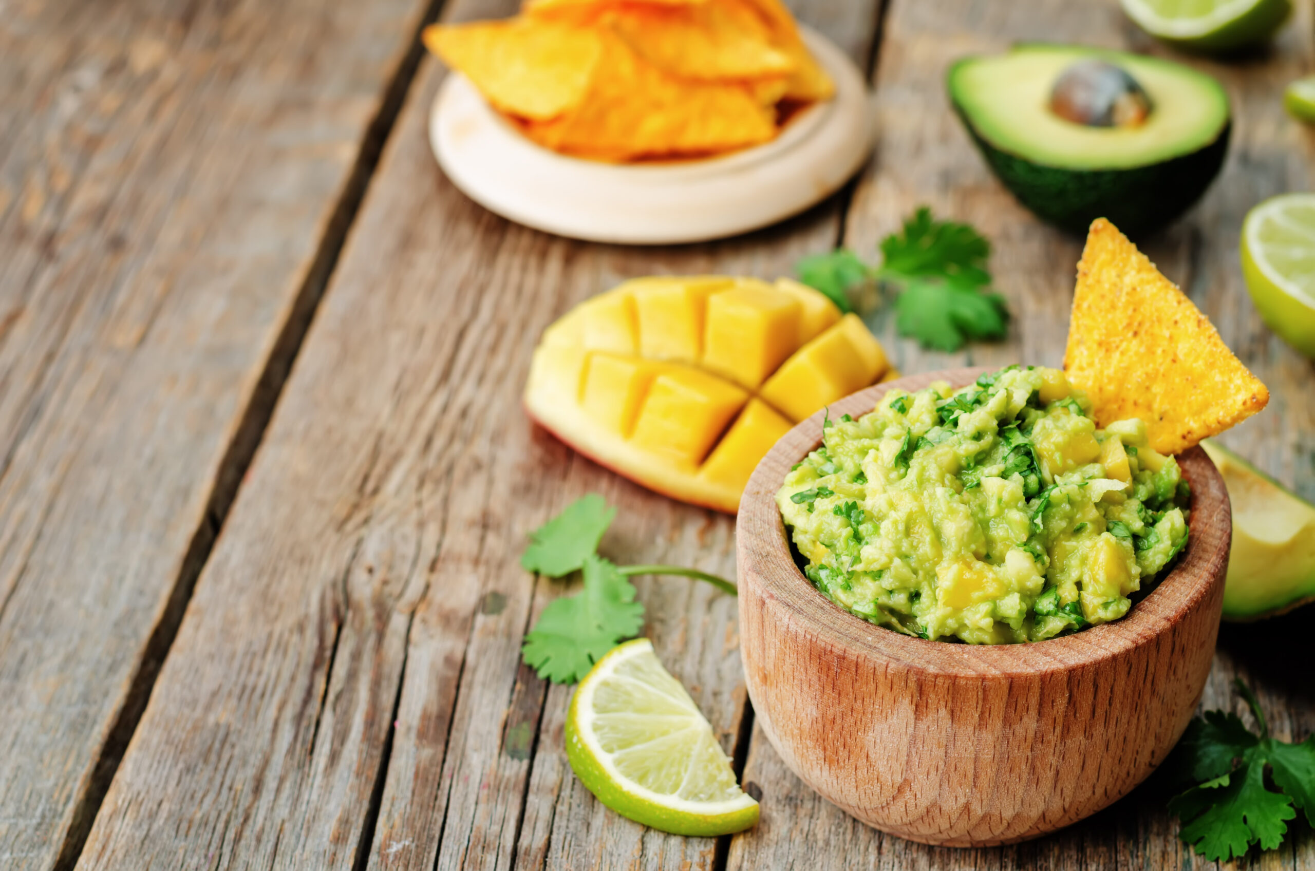 mango guacamole with corn chips on a dark wood background. the toning. selective focus