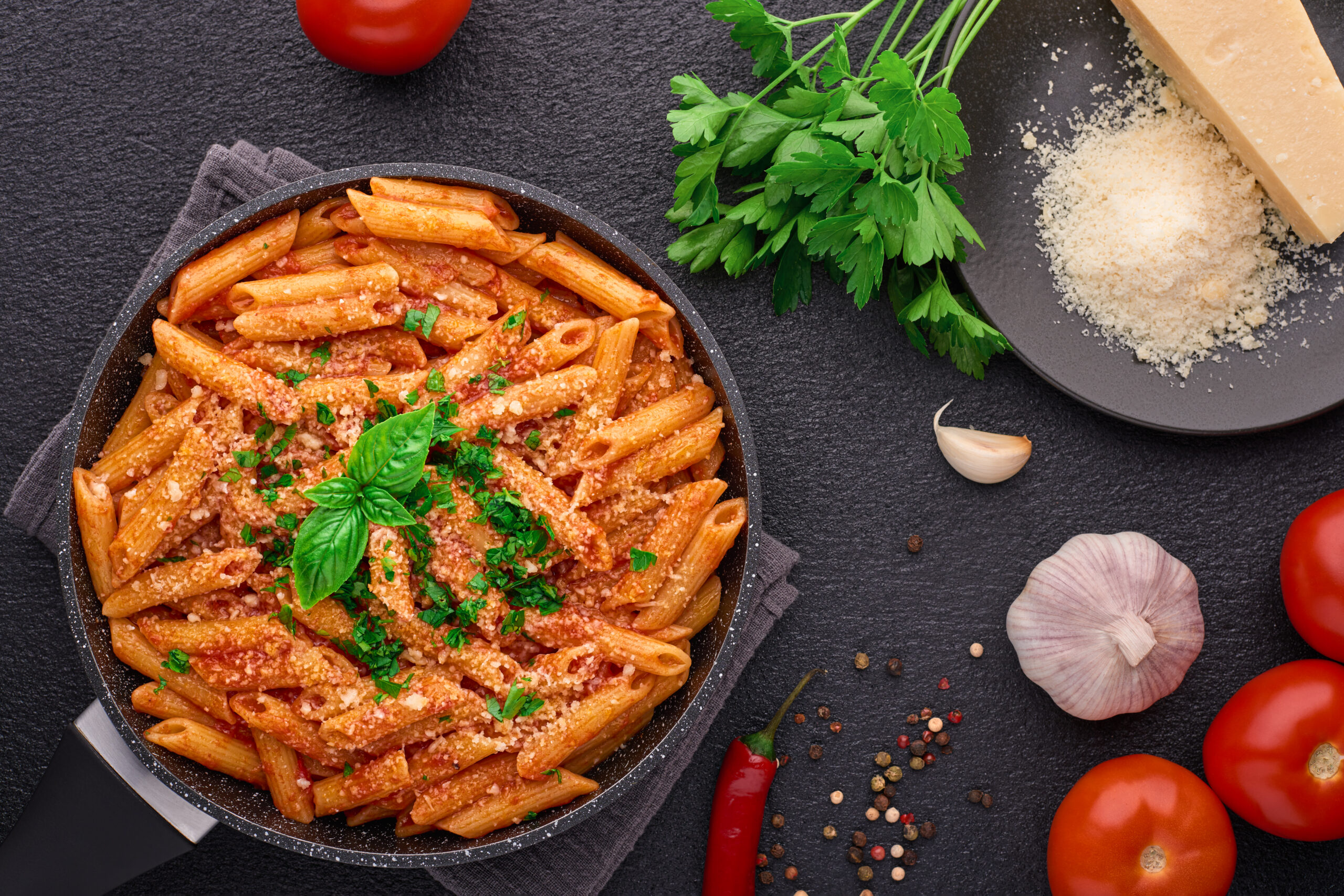 Frying pan with Penne All’arrabbiata pasta cooked according to a traditional Italian recipe and ingredients top view Frying pan with Penne All'arrabbiata pasta cooked according to a traditional Italian recipe and ingredients top view