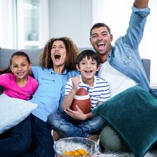 Family watching american football match on television at home