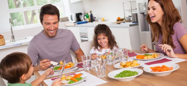 Family laughing around a good meal in kitchen