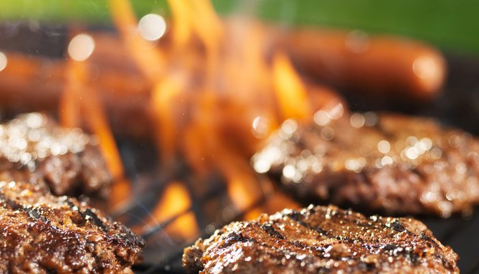 hamburgers and hotdogs cooking on flaming grill hamburgers and hotdogs cooking on flaming grill shot with selective focus