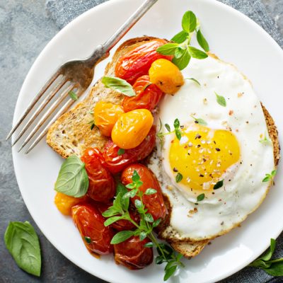 Multigrain toast with fried egg, fresh herbs and roasted tomatoes